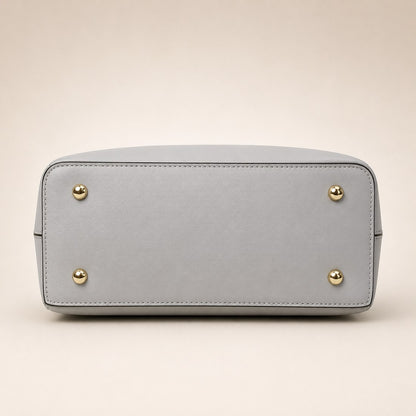 Light gray handbag with gold studs on a beige background