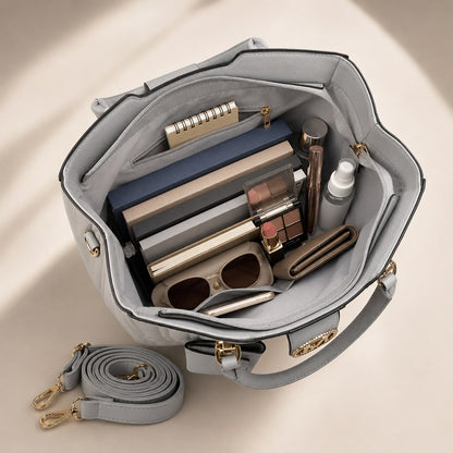 Gray handbag open to reveal makeup and skincare products on a beige background