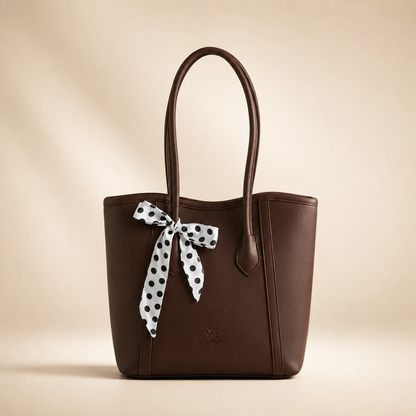 Brown handbag with a polka dot ribbon on a beige background