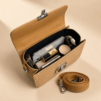 Open beige handbag with cosmetic items and a strap on a beige background