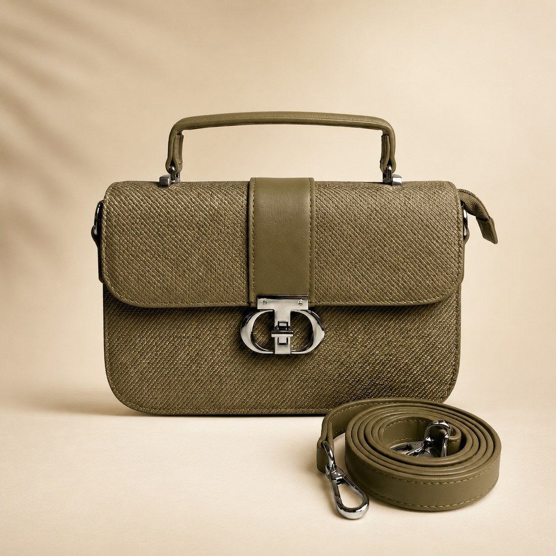 Green handbag with matching strap on a beige background
