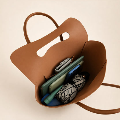 Brown leather bag with electronic devices inside on a beige background